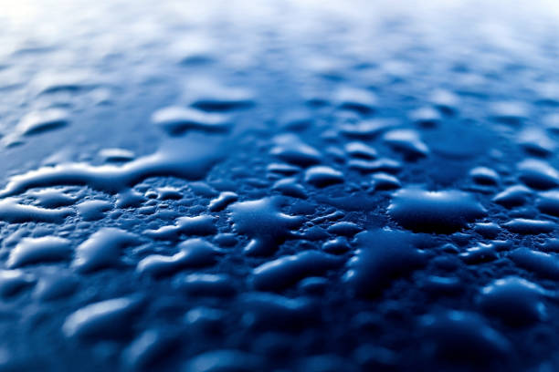 Condensed dewdrops on the smooth blue surface of a metallic car.