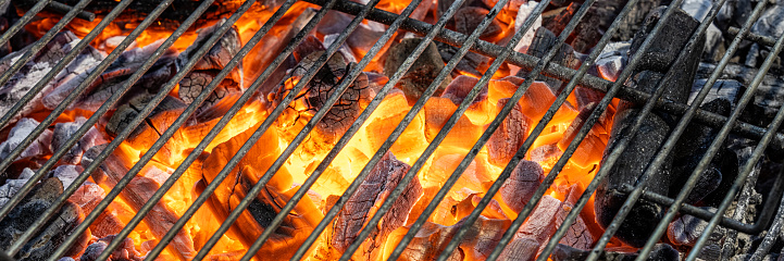 Close-up photo of blazing hot charcoal underneath a wire grid of a barbecue grill.