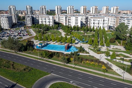 Aerial view of a neighborhood with modern white apartment buildings and recreational green areas.