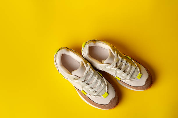 istock Beige sport running shoes on yellow studio background 1714613394