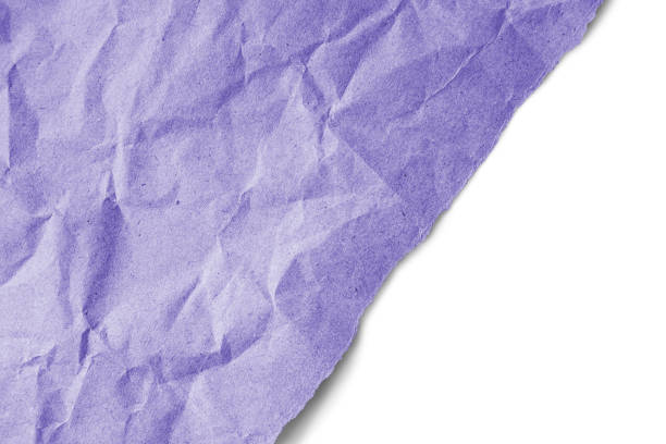istock Recycled crumpled purple paper texture with a diagonal torn edge isolated on white background 1714637292