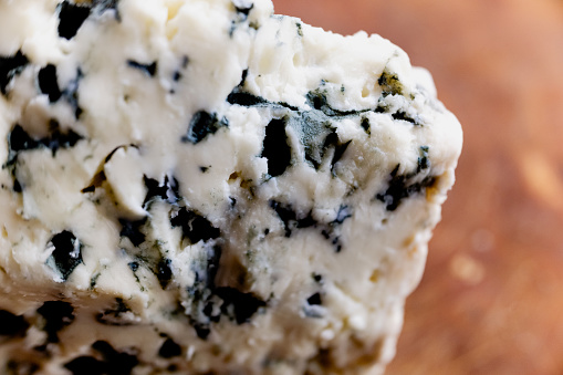 Macro close-up of a French blue cheese roquefort, tangy, crumbly and slightly moist, with distinctive veins of blue mold.