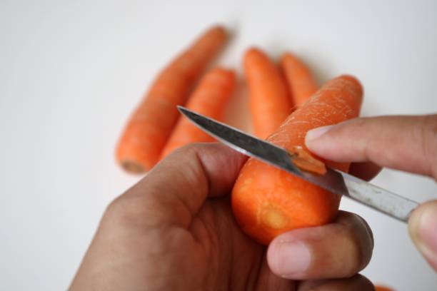 istock Hand peeling carrot skin with knife. 1714674163
