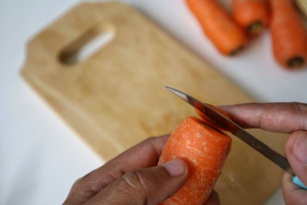 istock Hand peeling carrot skin with knife. 1714677329