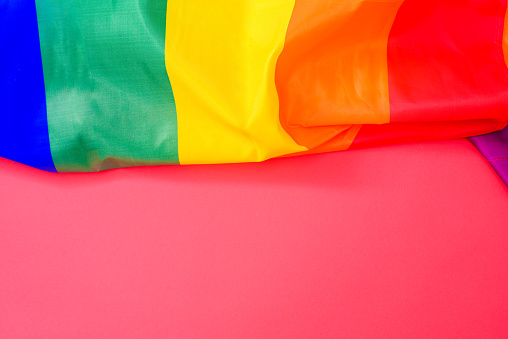 Red background with space for text, with the rainbow flag of the lgtbi movement at the top.