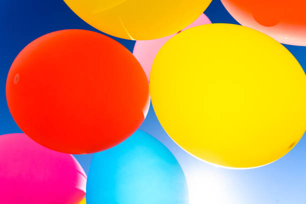 Pretty sunlit solid color balloons viewed from below with blue sky background