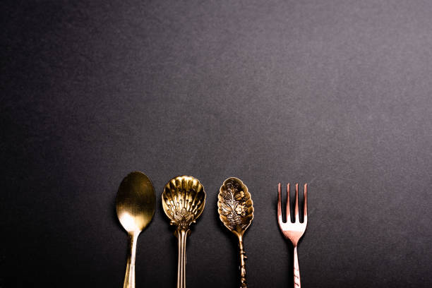 Retro style luxury cutlery on a black background, clean spoons and forks.