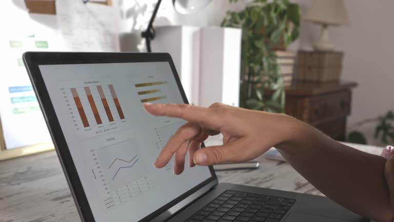 Woman making graphs and charts on laptop and reading data that she typed