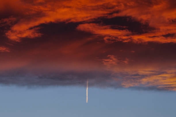 flugzeug kreuzend am launischen himmel - vapor trail sky night sunset stock-fotos und bilder