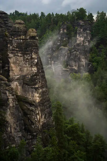 Picture of rock formation near the  Basteibridge in Germany during the morning on a cloudy day with some fog hanging around