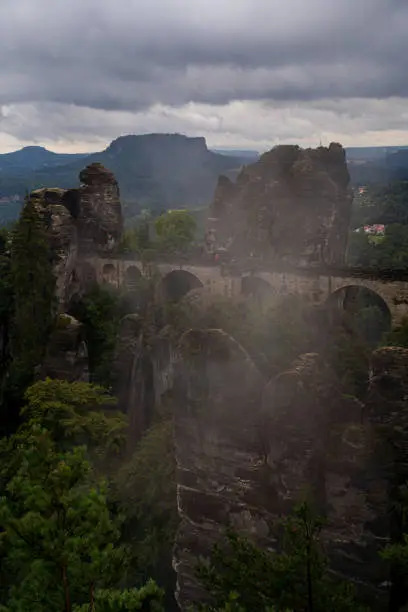 The Basteibridge in Germany during the morning on a cloudy day with some fog hanging around