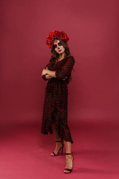 Mexican woman in dress dancing at national holiday Santa Muerte in mask in form of skull on isolated background stock photo