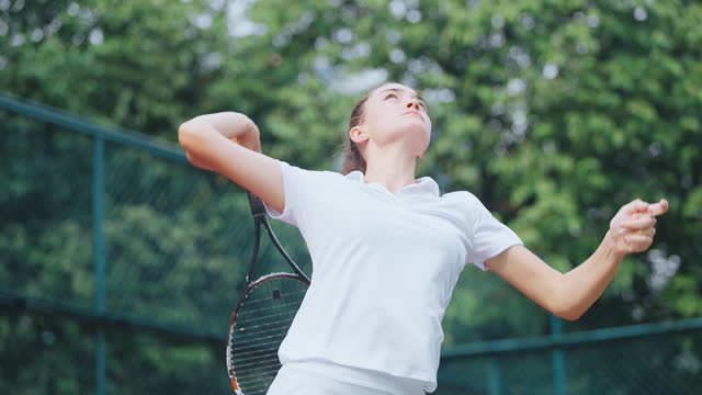 Teenage girl tennis player serving in tennis court