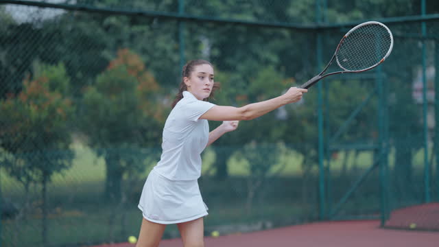One teenage girl tennis player practicing playing in tennis court