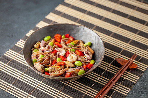 Japanese soba noodles with vegetables, edamame beans and seafood. Asian cuisine