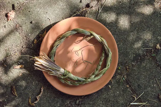 Sweetgrass braid (Hierochloe odorata), also called vanilla grass, holy grass or mary's grass, on a clay plate. Sweetgrass is widely used by Indigenous peoples from in North America to attract good spirits. Top shot, photographed directly above outdoors in summer on a sunny day.