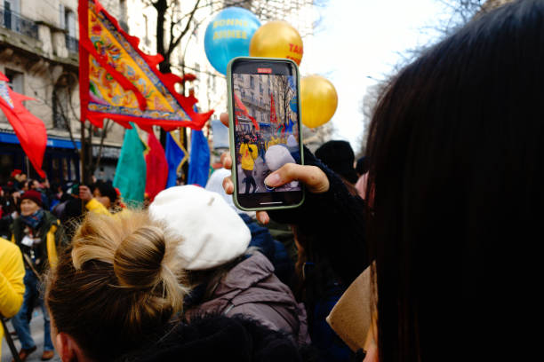 France - Paris 13th district - 20/12/2022 A young woman films the Chinese New Year parade with her smartphone.