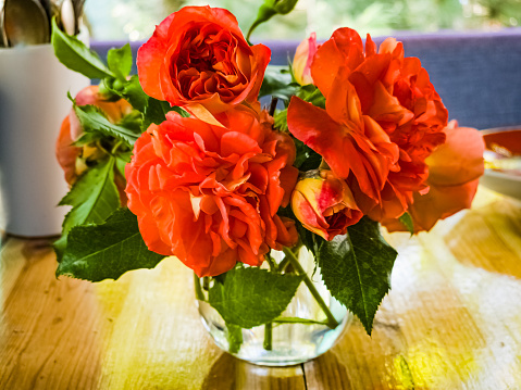 A bouquet of red roses in a glass on the table. Bouquet of roses in a rustic style.