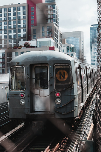 Typical New York City subway train between buildings approaching to a station.