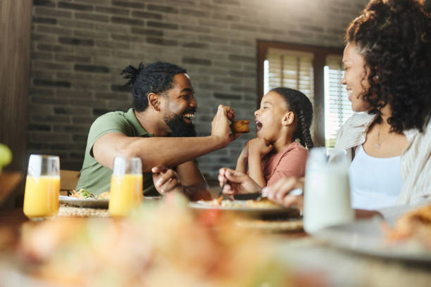 istock Happy black father feeding his daughter during breakfast at dining table. 1714799911