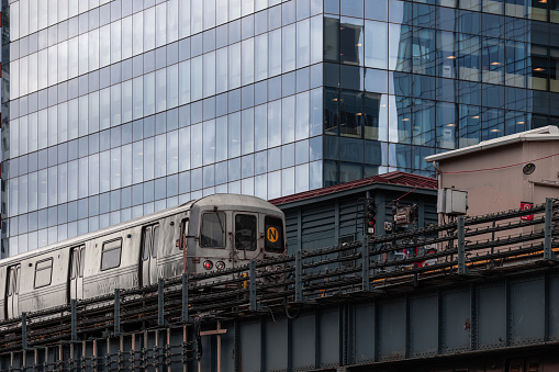 A New York City subway train departing from a elevated subway station in Queens.