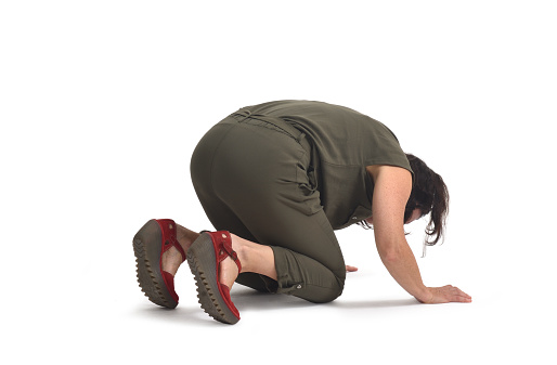side view of a woman on her knees searching or staring at something on the floor on white background
