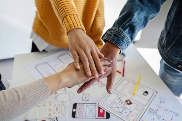 istock Asian ux developer and ui designer team stacking hands together, celebrating completion of project 1714808973