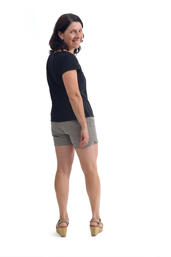 Back view of woman in shorts turning and looking at camera on white background.
