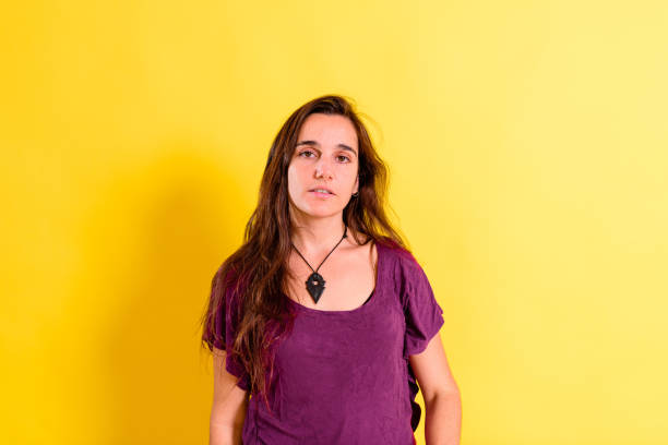 portrait of pretty 25 years old real girl without makeup posing looking at camera isolated on yellow studio background. - women spain 20 25 years adult imagens e fotografias de stock