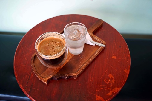 Angle veiw of a hot coffee cup with a water glass on wooden table in coffee shop.