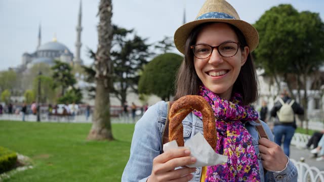 Young Woman Eating A Turkish Bagel In Front Of Blue Mosque In Istanbul
