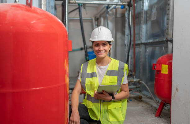 ritratto di ingegnere femminile che controlla il sistema di stoccaggio dell'acqua - water heater boiler water pipe basement foto e immagini stock