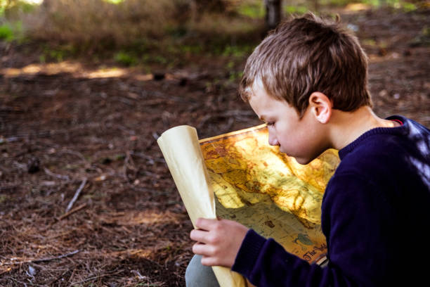 A clever boy searches an ancient map for something buried in a forest.