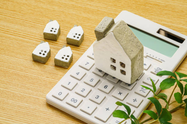 istock Calculator and miniature house on wooden table 1714841211