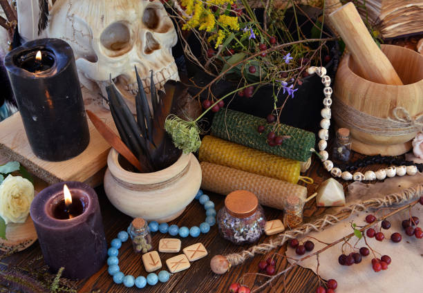 istock Black candles, magic wands and witch pot with herb on altar table. Occult, esoteric and divination still life. Mystic Halloween background with vintage objects for magic ritual 1714849454