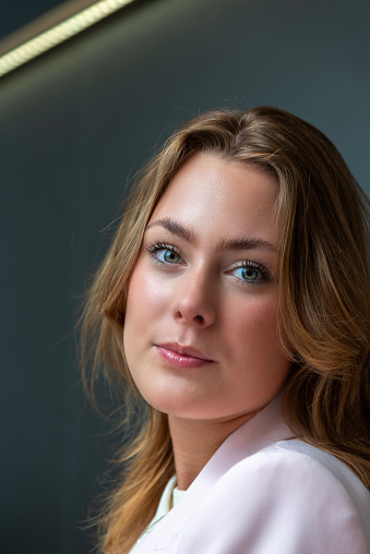 Portrait of a young  woman against a dark grey wall.