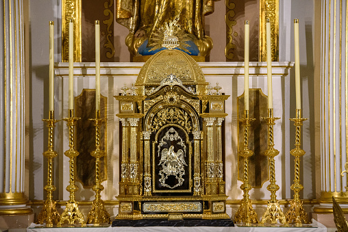 A gilt reliquary lavishly decorated in gold, inside a Catholic church.