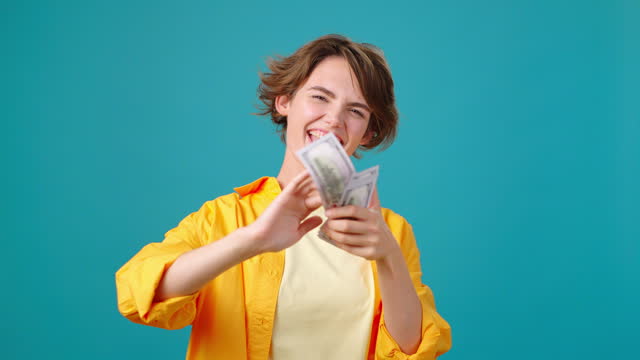 Wealthy young woman scatters dollar bills around laughing