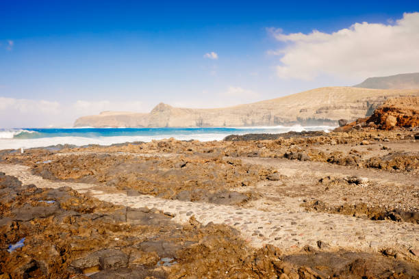 Atlantic rocky coast washed by the ocean on a sunny day with blue sky.