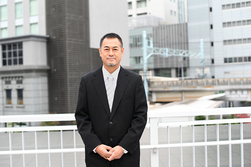 Middle-aged Asian businessman in a suit standing in the city
