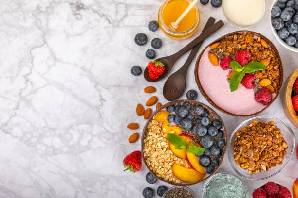 istock Useful breakfast. Granola bowl with yogurt and fresh berries on a textured kitchen table.Acai and spirulina bowl.Bowl of Greek yogurt with granola, almonds, blueberries, raspberries and strawberries 1714902885