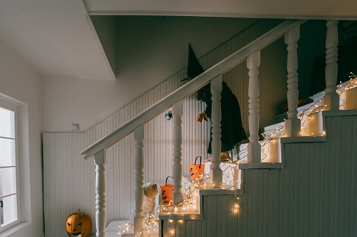 Teenagers dressed in halloween costumes sitting on the stairs on a Halloween party at home