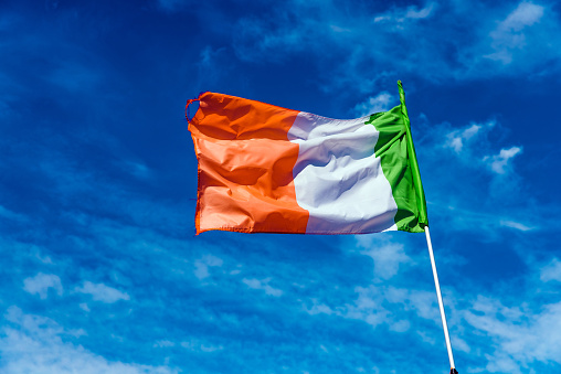 Flag of italy waving against the blue sky with clouds.