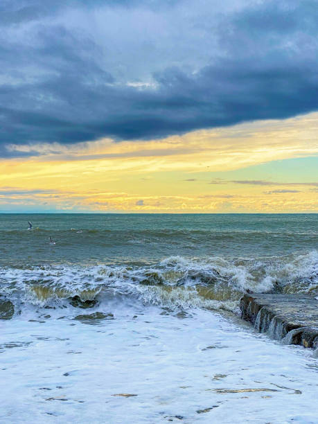 istock Black sea shore at sunset. Dramatic sky with glowing clouds, waves and water splashes. 1714947495