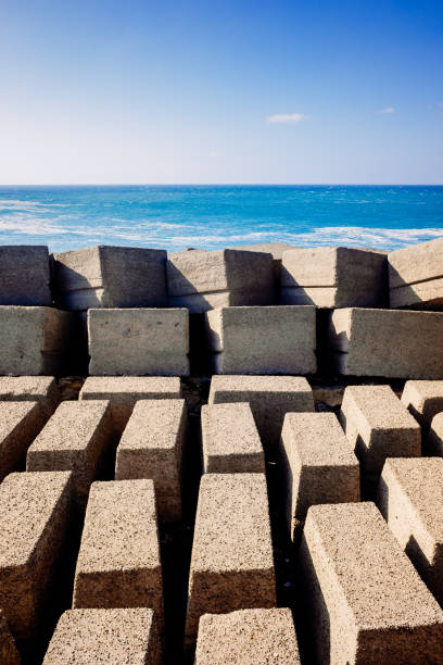 blocchi di pietra su una diga di un frangiflutti portuale sulla costa atlantica in una giornata di sole. - sea defence concrete foto e immagini stock