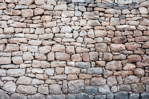 Stone wall with straight natural rocks, muted colors, rough background.