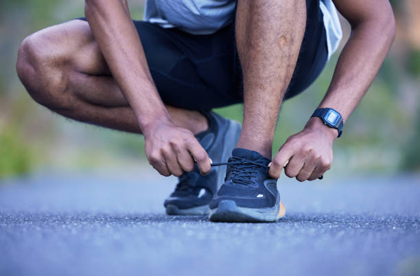 istock Fitness, exercise and a man tying shoelace outdoor for run, workout or training performance. Closeup of athlete person or runner with running shoes on a road for cardio or health and wellness 1714962881