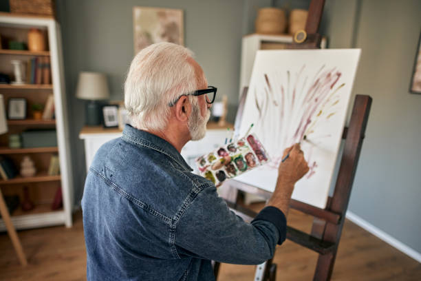 istock Elderly man painting on a canvas at home 1714977366