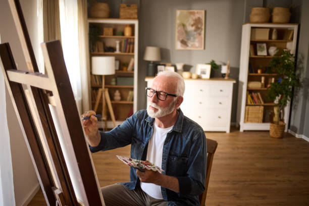 istock Elderly man painting on a canvas at home 1714978486