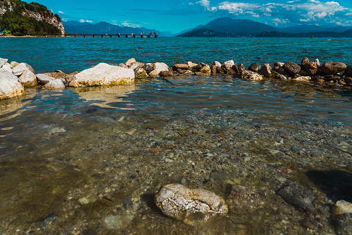 Wet rocks with views of Lago di Garda and the Alpine mountains in the background.